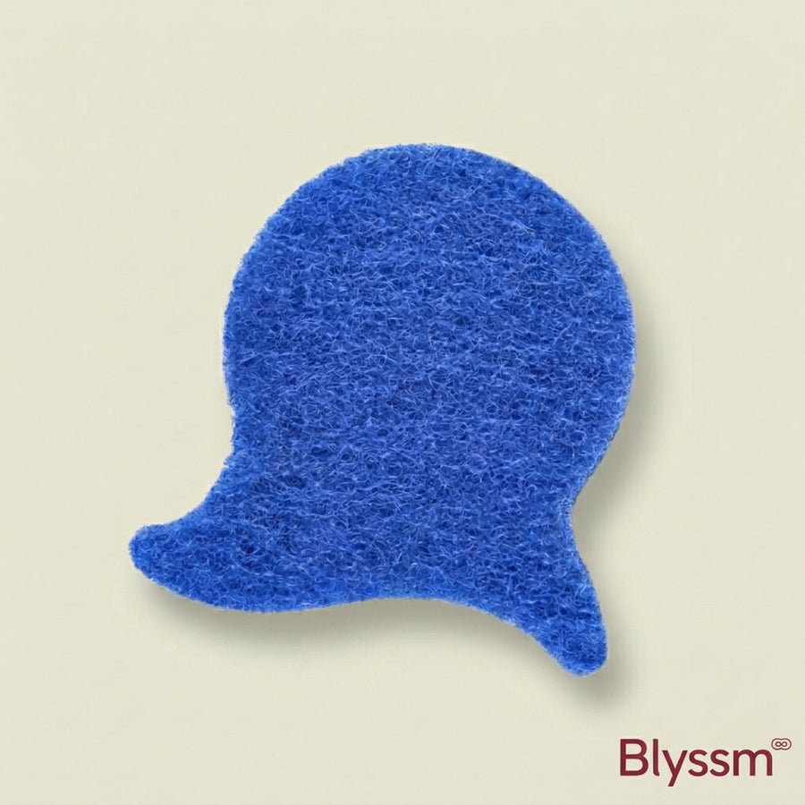 Blyssm Laundry Fur Catcher, blue fish-shaped fibre pad for pet hair and lint, flat lay on a cream background
