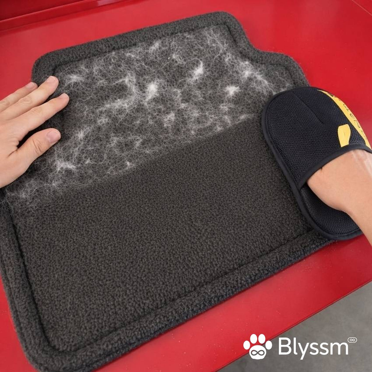 Blyssm grooming glove removing pet hair from a car floor mat
